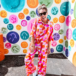 Thin, lightweight and stretchy set featuring fuchsia, orange, coral and ivory abstract print with 1/4 gold button front and collar on the short sleeved top and matching wide leg pants with elastic waist and pockets.
