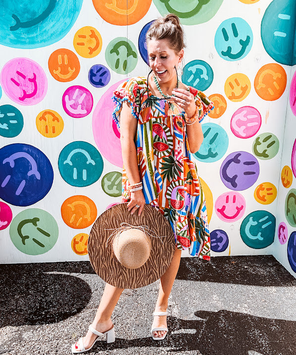 This tropical print short dress features vibrant summer hues with playful striping and fruit motifs throughout, square smocked neckline and flutter sleeves and pockets—complete with pink and blue ball tassels. Crafted from soft, lightweight fabric, it's designed to move with you all day long.