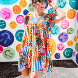 This tropical print short dress features vibrant summer hues with playful striping and fruit motifs throughout, square smocked neckline and flutter sleeves and pockets—complete with pink and blue ball tassels. Crafted from soft, lightweight fabric, it's designed to move with you all day long.