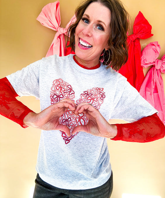 Light grey heathered tee with a pink and red heart made of bows on the front.