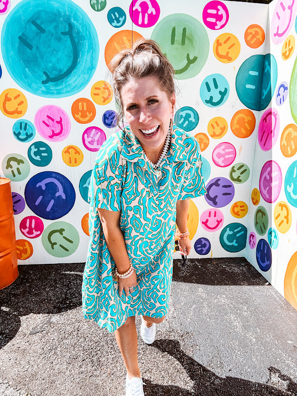 Teal and tan patterned mini dress with 1/4 button front and collar with short sleeves and pockets, fully lined.