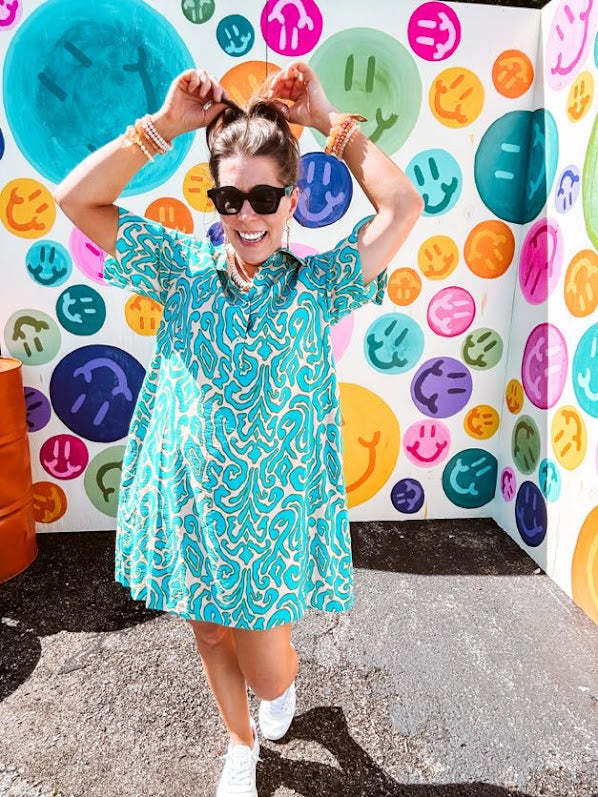 Teal and tan patterned mini dress with 1/4 button front and collar with short sleeves and pockets, fully lined.