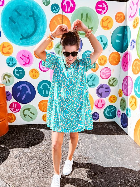 Teal and tan patterned mini dress with 1/4 button front and collar with short sleeves and pockets, fully lined.