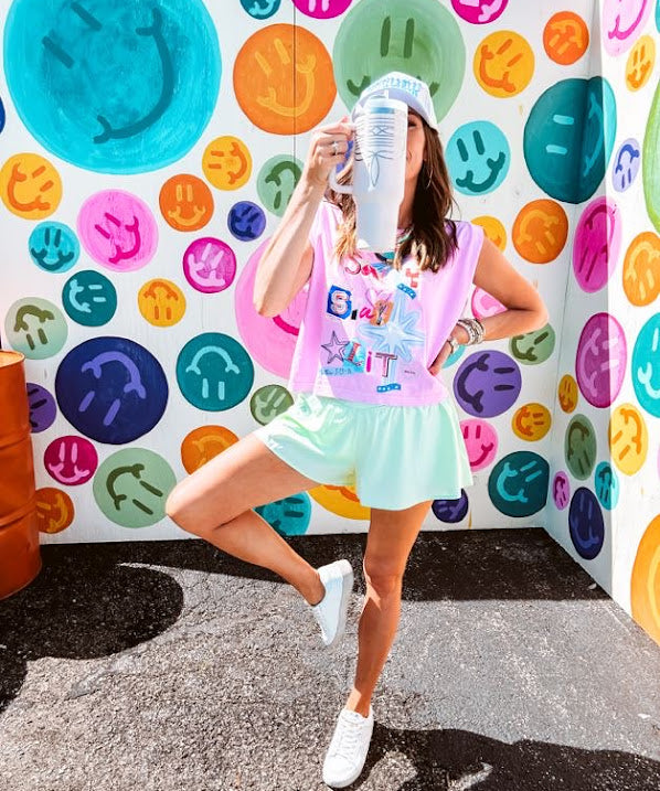 Cool pink cotton sleeveless tee with a shorter hemline with "Be Salty Stay Lit" multi colored retro inspired graphic on the front.