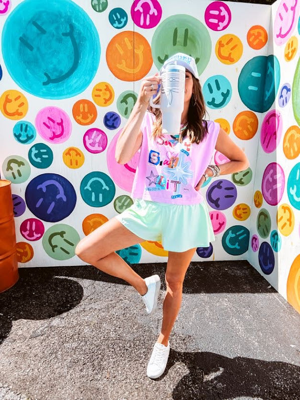 Cool pink cotton sleeveless tee with a shorter hemline with "Be Salty Stay Lit" multi colored retro inspired graphic on the front.
