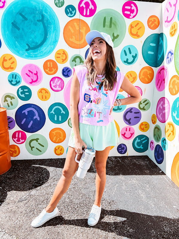 Cool pink cotton sleeveless tee with a shorter hemline with "Be Salty Stay Lit" multi colored retro inspired graphic on the front.