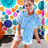 Light blue and white geometric short sleeved button down with collar and cuffed sleeves with bold orange, green and pink embroidery on the shoulders.