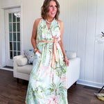 Fully lined flowy halter dress in seafoam green with green and coral tropical print, V neck with button option, matching silky belt and pockets. Midi length.