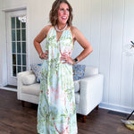 Fully lined flowy halter dress in seafoam green with green and coral tropical print, V neck with button option, matching silky belt and pockets. Midi length.