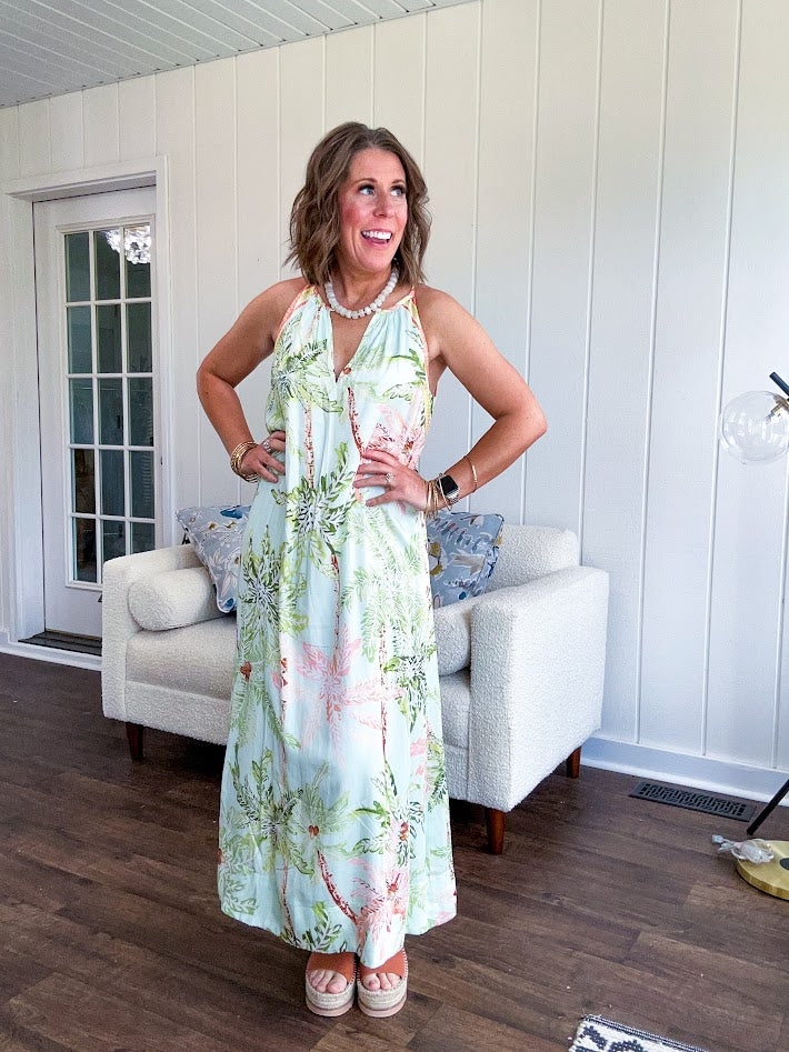 Fully lined flowy halter dress in seafoam green with green and coral tropical print, V neck with button option, matching silky belt and pockets. Midi length.