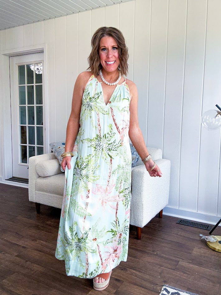 Fully lined flowy halter dress in seafoam green with green and coral tropical print, V neck with button option, matching silky belt and pockets. Midi length.