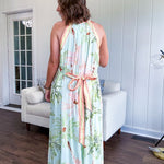 Fully lined flowy halter dress in seafoam green with green and coral tropical print, V neck with button option, matching silky belt and pockets. Midi length.