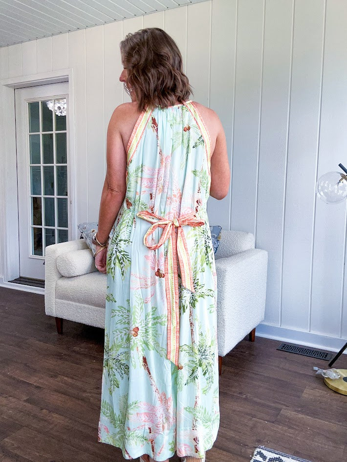 Fully lined flowy halter dress in seafoam green with green and coral tropical print, V neck with button option, matching silky belt and pockets. Midi length.