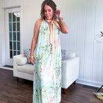 Fully lined flowy halter dress in seafoam green with green and coral tropical print, V neck with button option, matching silky belt and pockets. Midi length.