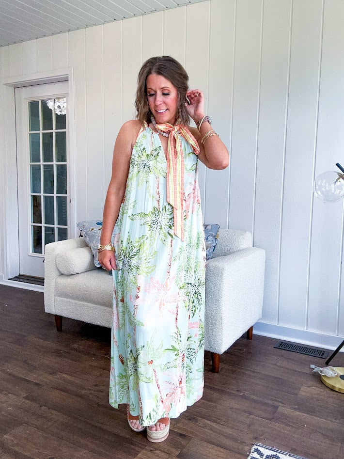 Fully lined flowy halter dress in seafoam green with green and coral tropical print, V neck with button option, matching silky belt and pockets. Midi length.