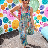 Cotton denim overalls with adjustable straps and sides with metal buttons in a paint splatter detail in cobalt blue, orange, green and yellow washed color with knee darts.