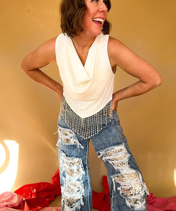White cropped tank with draped neckline, pointed hemline and pearl fringe.