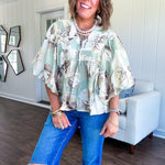 Flowy sage and ream floral blouse with billow sleeve, V neck with a tie and flowy hem.