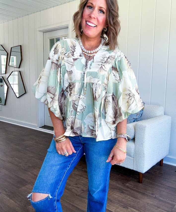 Flowy sage and ream floral blouse with billow sleeve, V neck with a tie and flowy hem.