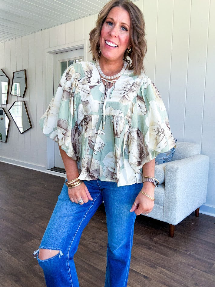 Flowy sage and ream floral blouse with billow sleeve, V neck with a tie and flowy hem.