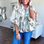 Flowy sage and ream floral blouse with billow sleeve, V neck with a tie and flowy hem.