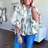 Flowy sage and ream floral blouse with billow sleeve, V neck with a tie and flowy hem.