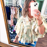 Flowy sage and ream floral blouse with billow sleeve, V neck with a tie and flowy hem.