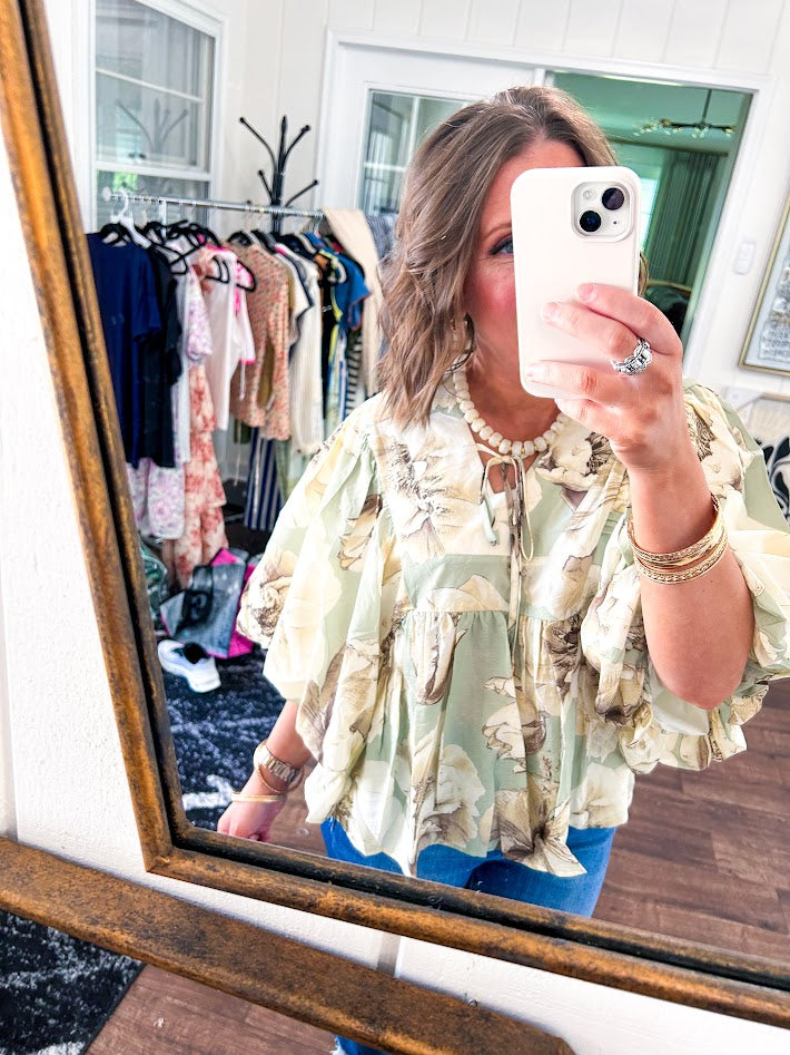 Flowy sage and ream floral blouse with billow sleeve, V neck with a tie and flowy hem.