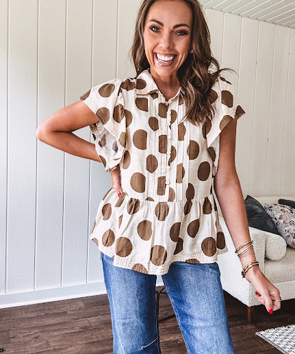 Lightweight and flowy cream top with khaki polka dots throughout with flutter sleeve 3/4 button down front and ruffle hem with pintucking down the placket.