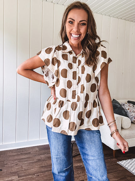 Lightweight and flowy cream top with khaki polka dots throughout with flutter sleeve 3/4 button down front and ruffle hem with pintucking down the placket.