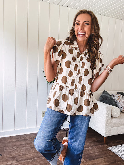 Lightweight and flowy cream top with khaki polka dots throughout with flutter sleeve 3/4 button down front and ruffle hem with pintucking down the placket.