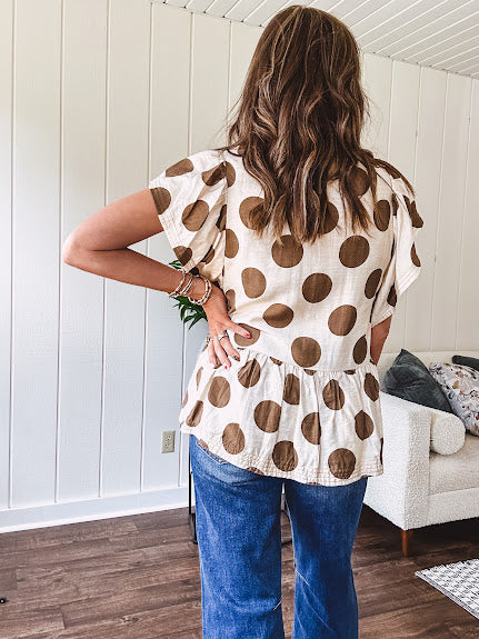 Lightweight and flowy cream top with khaki polka dots throughout with flutter sleeve 3/4 button down front and ruffle hem with pintucking down the placket.