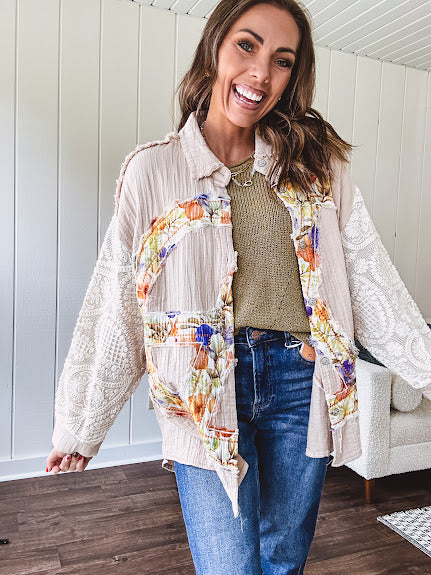 Beige cotton shacket with floral peace patch across the front, lace sleeves and metal buttons down the front. Oversized.