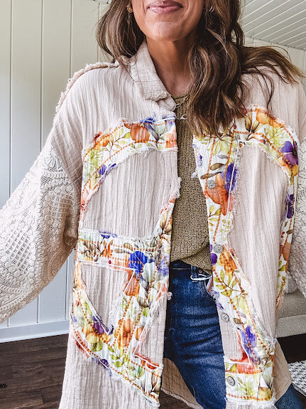 Beige cotton shacket with floral peace patch across the front, lace sleeves and metal buttons down the front. Oversized.