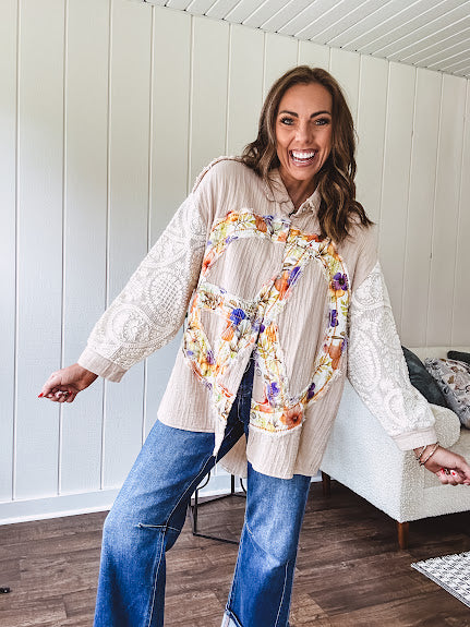 Beige cotton shacket with floral peace patch across the front, lace sleeves and metal buttons down the front. Oversized.