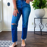 High rise dark wash denim with button and zipper closure, stretch, distressing at the knee and raw hem with straight leg.