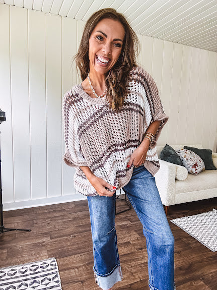Soft open weave drop shoulder pullover with taupe, dark grey and white striping throughout, V neck design front and back and oversized fit.