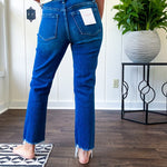 High rise dark wash denim with button and zipper closure, stretch, distressing at the knee and raw hem with straight leg.