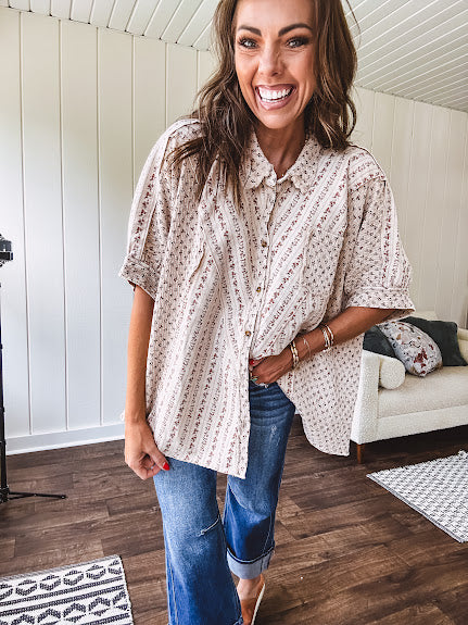 Oversized cotton blend khaki dolman style button front top with raw seams, cuffed short sleeves and dainty floral patterns in spice with mixed textures.