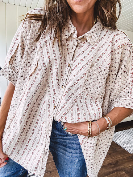 Oversized cotton blend khaki dolman style button front top with raw seams, cuffed short sleeves and dainty floral patterns in spice with mixed textures.