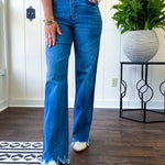 Medium wash ultra high rise straight leg jeans with no distressing throughout, but distressed hem.