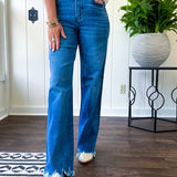Medium wash ultra high rise straight leg jeans with no distressing throughout, but distressed hem.