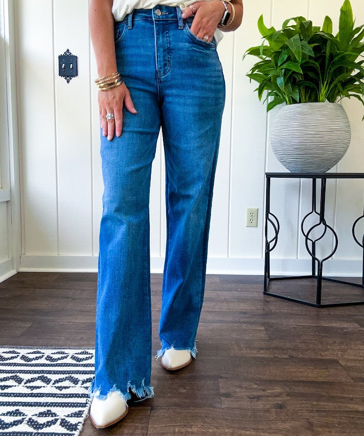 Medium wash ultra high rise straight leg jeans with no distressing throughout, but distressed hem.