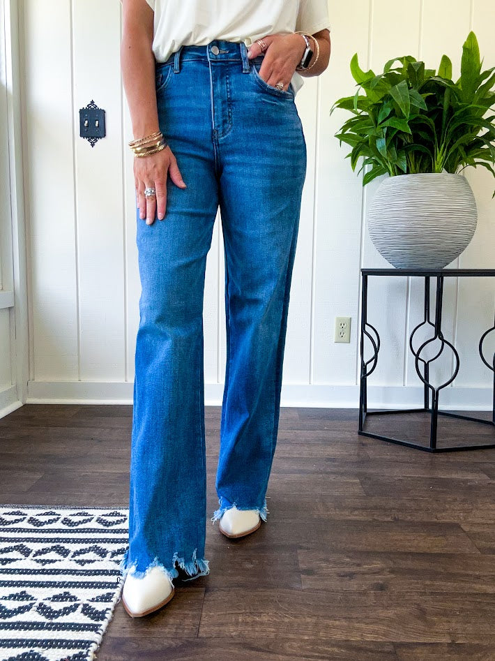 Medium wash ultra high rise straight leg jeans with no distressing throughout, but distressed hem.