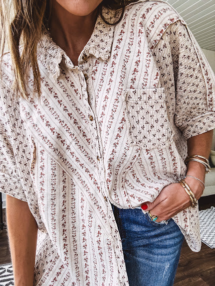 Oversized cotton blend khaki dolman style button front top with raw seams, cuffed short sleeves and dainty floral patterns in spice with mixed textures.