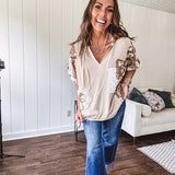 Oversized, lightweight stretchy beige ribbed top with a mix of wheat and dark tan crochet inserts and trim throughout with ivory crochet florals, hoodie and lace drawstring with lace at the wide hem and short sleeved cuffs.
