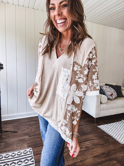 Oversized, lightweight stretchy beige ribbed top with a mix of wheat and dark tan crochet inserts and trim throughout with ivory crochet florals, hoodie and lace drawstring with lace at the wide hem and short sleeved cuffs.