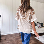 Oversized, lightweight stretchy beige ribbed top with a mix of wheat and dark tan crochet inserts and trim throughout with ivory crochet florals, hoodie and lace drawstring with lace at the wide hem and short sleeved cuffs.