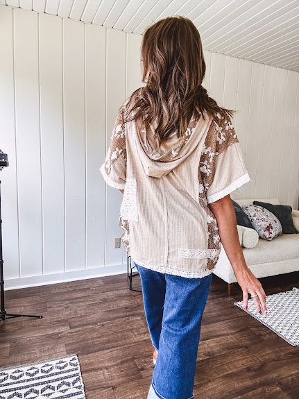 Oversized, lightweight stretchy beige ribbed top with a mix of wheat and dark tan crochet inserts and trim throughout with ivory crochet florals, hoodie and lace drawstring with lace at the wide hem and short sleeved cuffs.