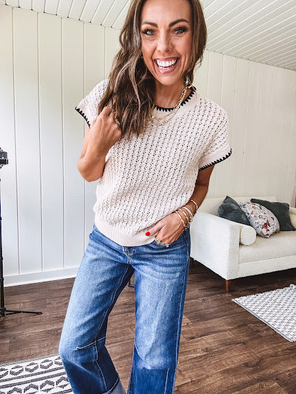 Light khaki crochet knit sweater with short sleeves and contrasting black trim at the round neck and cuffs with a wide ribbed hem.